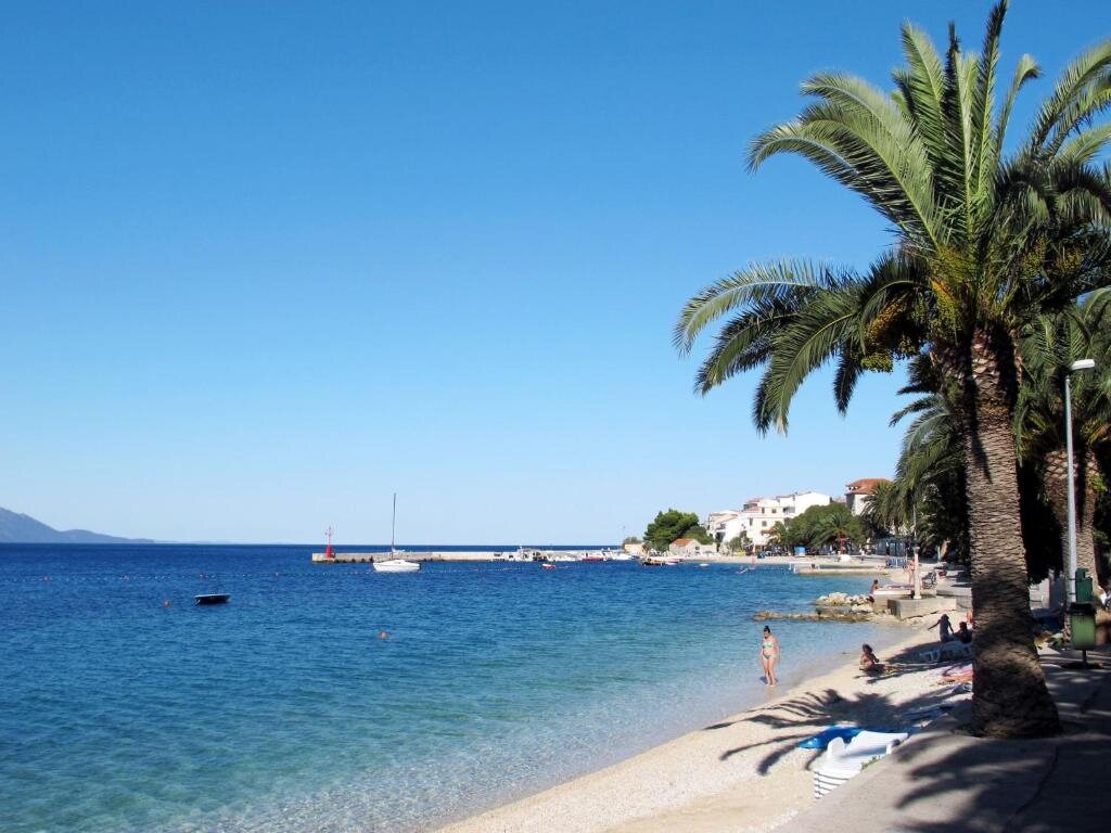 Šljunčana plaža s palmama i bistrim morem na Makarskoj rivijeri