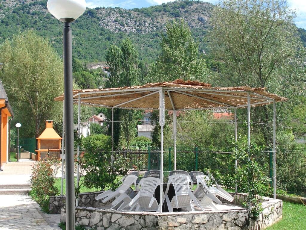 Natkrivena sjenica sa stolom i stolicama na kamenom podestu